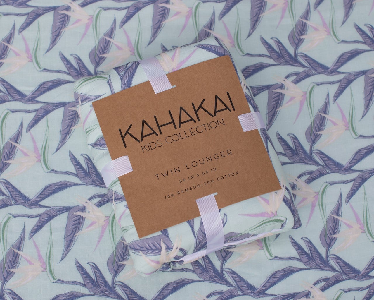Kahakai Kids Collection twin blanket on a leaf-patterned bedspread